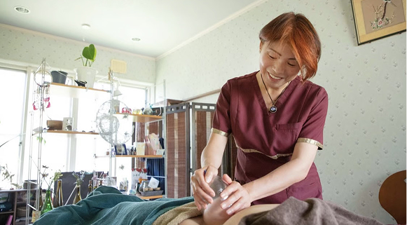 施術を受けている女性と寄り添うサロンのオーナー